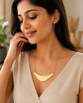Gold-tone crescent pendant necklace styled with a cream V-neck outfit
