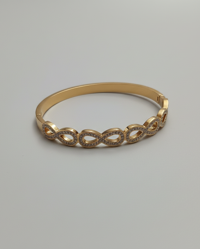 Gold infinity diamond cuff bracelet on white background
