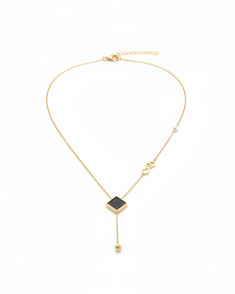 Gold lariat necklace with black square pendant on white background